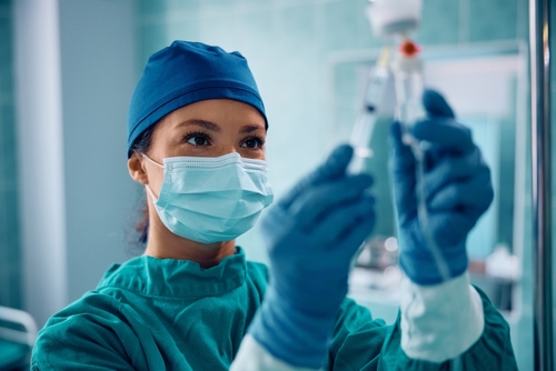 Female,Anesthesiologist,Injecting,Drugs,Through,Iv,Drip,Before,Surgical,Procedure